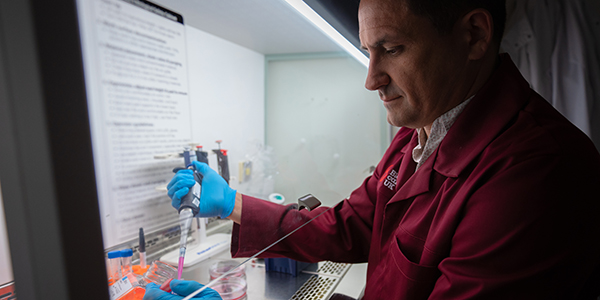 a researcher in a laboratory, putting liquid into a test tube